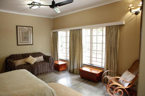 a room with a bed and a couch and windows at Down Gran's Self-Catering Cottage in Lobamba