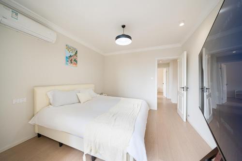 a white bedroom with a bed and a television at Today Aparthotel West Lujiazui Shanghai in Shanghai