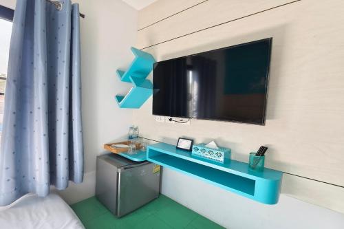 a room with a tv and a blue shelf at Lilliput Riverside Bangkachao in Samutprakarn