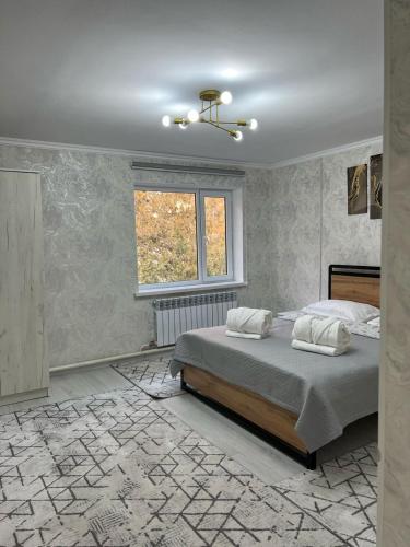 a bedroom with a bed and a window at Arbat Toktogul Hotel in Toktogul