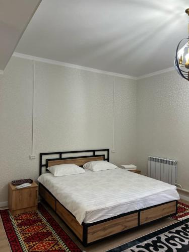 a bedroom with a large bed with white sheets at Arbat Toktogul Hotel in Toktogul