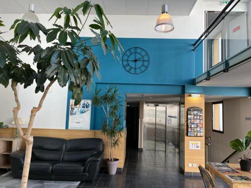 a lobby with a black couch and a clock on the wall at Peaceful studio in Idron in Idron