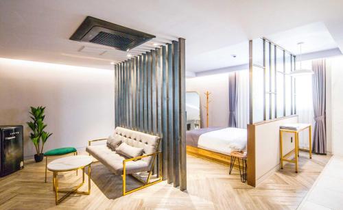 a bedroom with a bed and a couch and a chair at Hotel Crape Gyeongsan in Gyeongsan