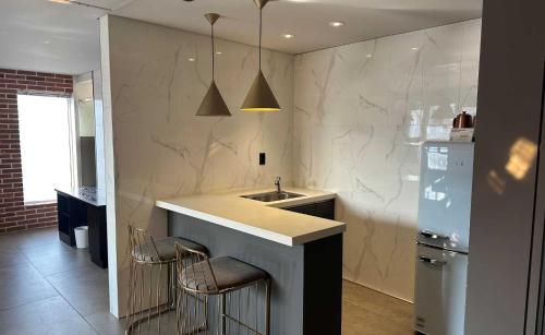 a kitchen with a sink and a counter with stools at Hotel Crape Gyeongsan in Gyeongsan