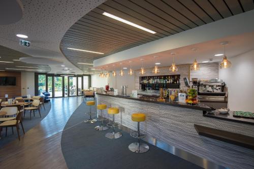 a restaurant with a bar with yellow stools at Maubreuil Séminaires in Carquefou