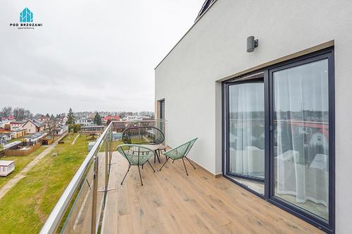a balcony with two chairs and a table on it at Pod Brzozami Apartamenty 5 Mórz in Ustronie Morskie