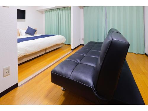 さいたま市にあるHOTEL Nishikawaguchi Weekly - Vacation STAY 43479vのベッド付きの客室で、黒い革張りのソファが備わります。