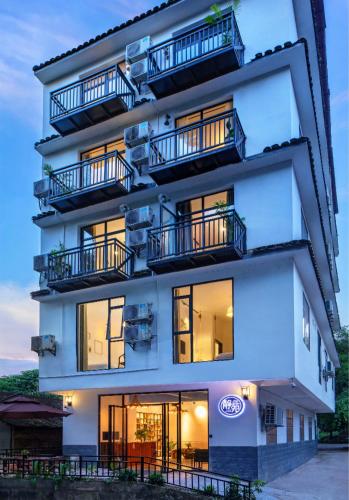 a tall white building with balconies on it at Yangshuo Jing Yuan Inn Near The West Street in Yangshuo