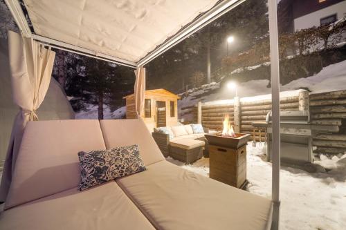 a tent with a bed and a fireplace in the snow at Glamping Špindl One&Only in Špindlerův Mlýn