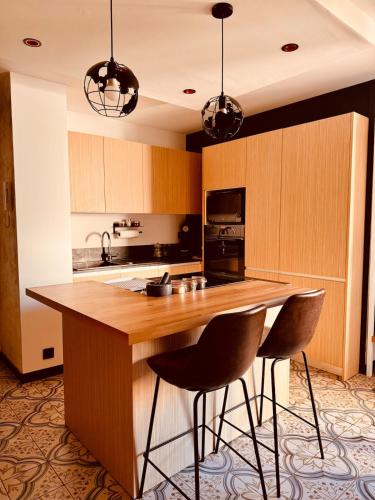 une cuisine avec un îlot en bois et deux tabourets de bar dans l'établissement Le Longo Maï ,2 chambres, parking gratuit, à La Garde