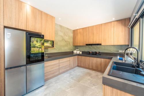 a kitchen with wooden cabinets and a stainless steel refrigerator at Merbrisa Rayong poolvilla-Ao khai beachfront in Mae Pim