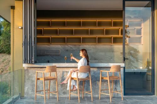 a woman sitting at a bar with a glass of wine at Merbrisa Rayong poolvilla-Ao khai beachfront in Mae Pim