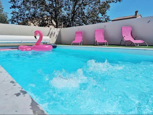 une piscine avec des chaises roses et un cygne rose dans l'établissement Villa 8 pers, Piscine privée, proche mer, à Maureillas