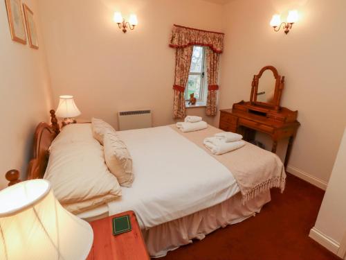 1 Schlafzimmer mit 2 Betten, einem Spiegel und einem Klavier in der Unterkunft Fern Cottage in Wooler