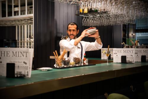 a man standing behind a bar with a drink at Vincci The Mint in Madrid