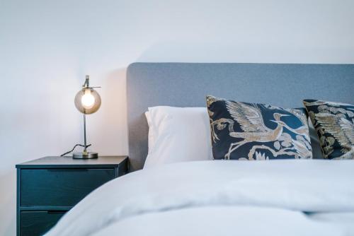 a bed with pillows and a lamp on a night stand at Modern 1BR Apartment in Central Warrington in Warrington