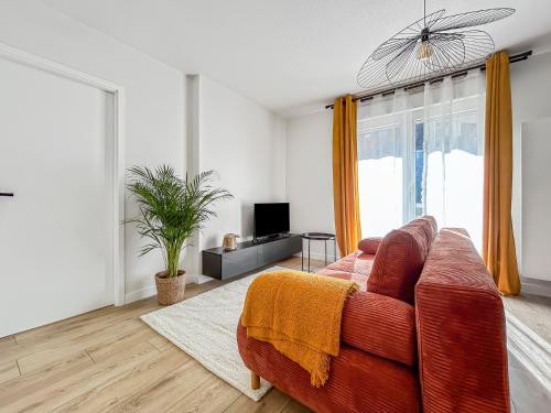 un salon avec un canapé rouge et une télévision dans l'établissement Saint-Louis - Cozy Apartment Close to Switzerland & Train Station, à Saint-Louis