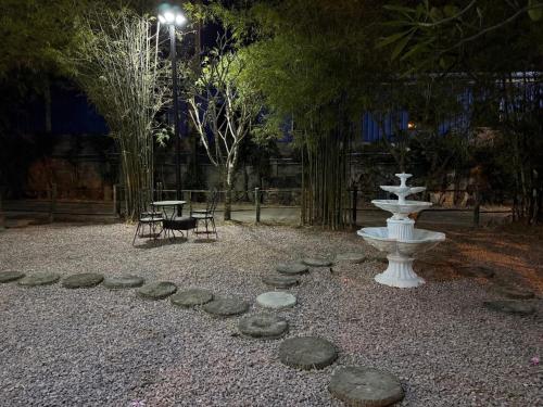 a garden with a fountain and rocks on the ground at Greeny cozy house in Ratchaburi