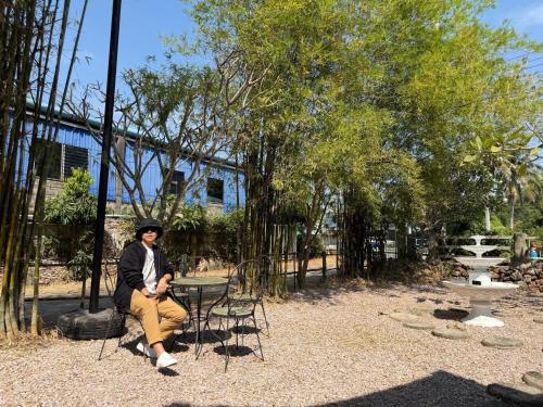 a man sitting at a table in a park at Greeny cozy house in Ratchaburi