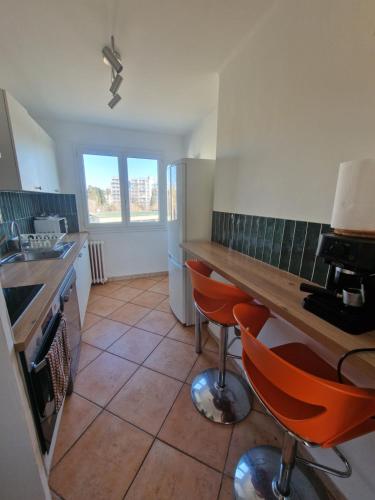 - une cuisine avec un comptoir et des chaises orange dans l'établissement Grand et Sapcieux T4 proche centre-ville, à Montpellier