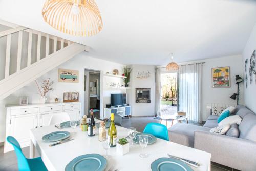 - un salon avec une table blanche et des chaises bleues dans l'établissement Villa Namibia - Jacuzzie - 500m Plage et Lac, à Seignosse