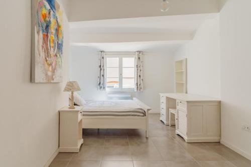 une chambre blanche avec un lit et un bureau dans l'établissement Aix Historique La Tour de l 'Horloge, à Aix-en-Provence