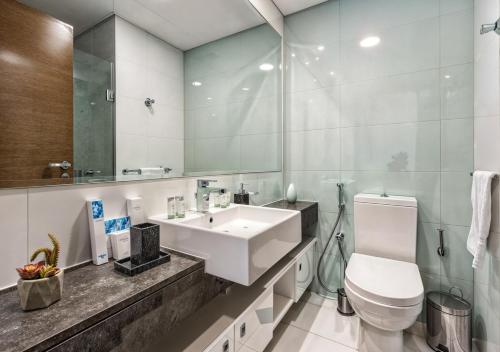 a bathroom with a sink and a toilet and a mirror at Desert Key - Platinum Apartments in Gate Tower, Al Reem Island in Abu Dhabi