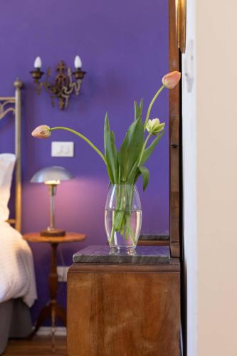 a vase with flowers on a table in a bedroom at 900 - Guest House in Livorno