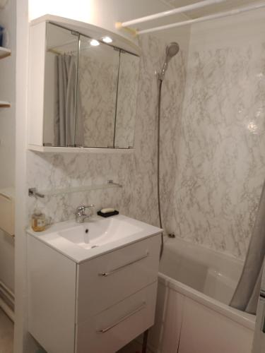 une salle de bain blanche avec un lavabo et une douche dans l'établissement Appartement, Résidence Grand Pavois, 28 rue Anatole France, lumineux, plein centre, tout à pied, parking privé, ascenseur, arrivée autonome,, au Havre