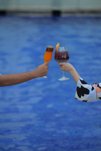 two people holding wine glasses in front of a pool at Novotel Hyderabad Airport in Hyderabad
