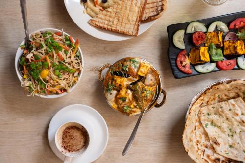 a table with plates of food and a bowl of food at Hotel Royal Central Haridwar in Haridwār