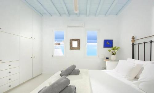 a white bedroom with a bed and a dresser at Paradisiacal Villa with Pool and Sea View in Mykonos in Agios Ioannis Mykonos