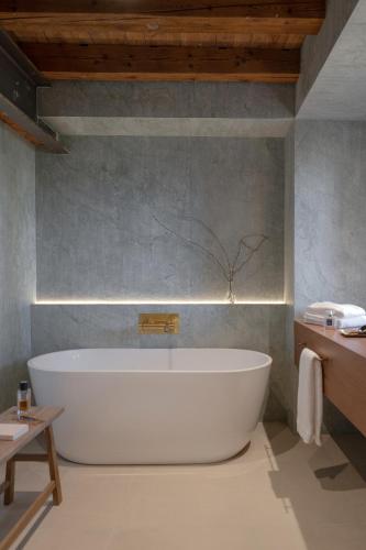 a large white bath tub in a bathroom at MiHotel - Grenier à Sel de Pérouges in Pérouges