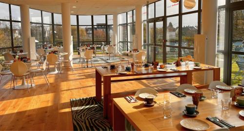 Un restaurante con mesas, sillas y ventanas. en Residhome Neuilly Bords De Marne, en Neuilly-Plaisance