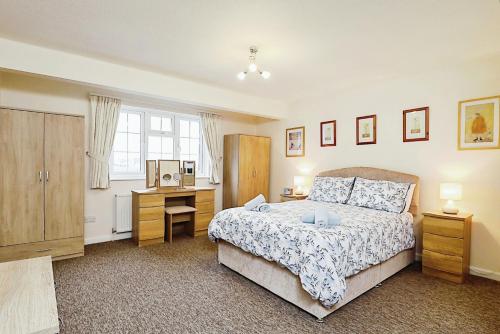 Un dormitorio con una cama y un escritorio y una ventana. en Helms House, en Saint Helens