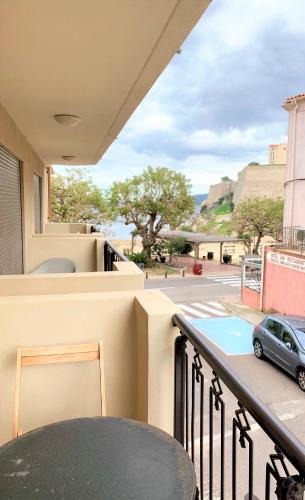 - un balcon avec une table et une voiture dans une rue dans l'établissement CALVI Centre ville Vue Mer au Calme, à Calvi