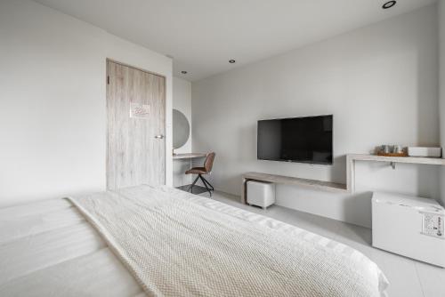 a white bedroom with a bed and a flat screen tv at Penghu SunSea Hall in Magong