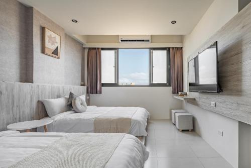 a hotel room with two beds and a tv at Penghu SunSea Hall in Magong