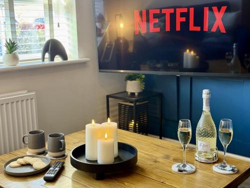a table with a candle and two glasses of wine at Modern 2-Bed House with EV - Hosted by Hutch Lifestyle in Warwick