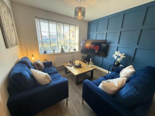 a living room with two blue couches and a table at Modern 2-Bed House with EV - Hosted by Hutch Lifestyle in Warwick
