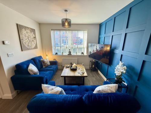 a living room with blue couches and a table at Modern 2-Bed House with EV - Hosted by Hutch Lifestyle in Warwick