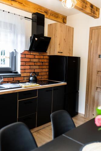 a kitchen with a stove and a black refrigerator at Beskid Loft House - domki w górach in Sól