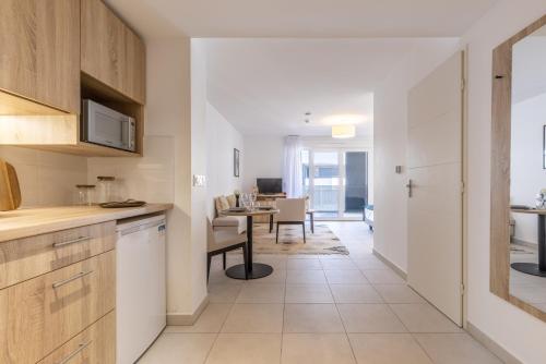 une cuisine avec des placards blancs et une salle à manger dans l'établissement Zenao Appart'hôtels Villeneuve Loubet, à Villeneuve-Loubet