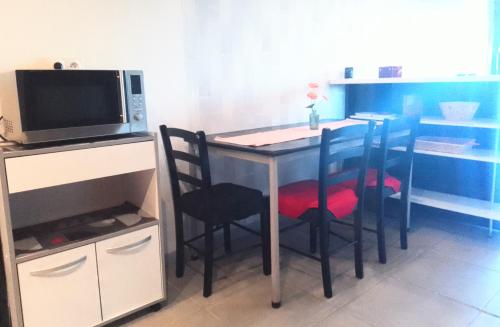une cuisine avec une table avec des chaises et un micro-ondes dans l'établissement appartement T2 TURSAN, à Bahus-Soubiran