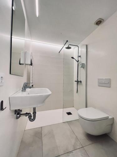 a white bathroom with a sink and a toilet at Hostal by El Collell TODO INCLUIDO in Sant Ferriol