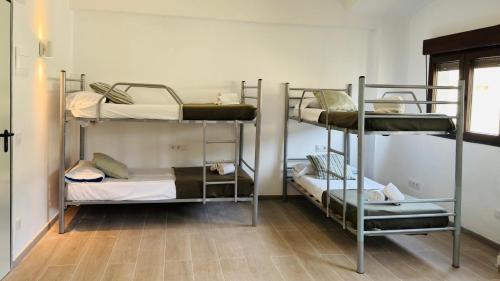 a room with three bunk beds and a wooden floor at Casa de colònies by El Collell TODO INCLUIDO in Sant Ferriol