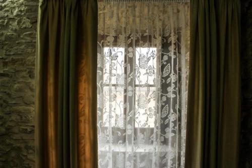 a window with white lace curtains in a room at Castel di Pietra in Pietra Montecorvino