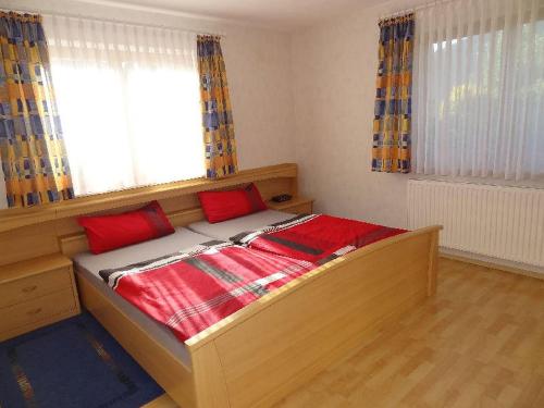 a bedroom with a bed with red pillows and a window at Ferienwohnung Bohnert in Fischerbach