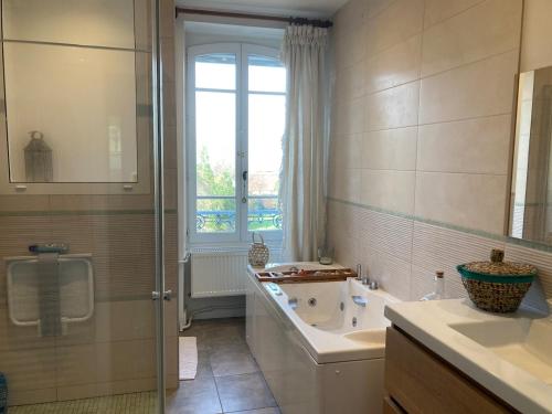une salle de bain avec une baignoire, un lavabo et une fenêtre dans l'établissement Beautiful 18th Century Whole Manor House with Sole Use Private Pool, à Gevingey