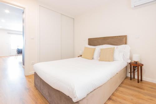 a white bedroom with a large white bed with pillows at Apartamento Porta14 1 in Chaves